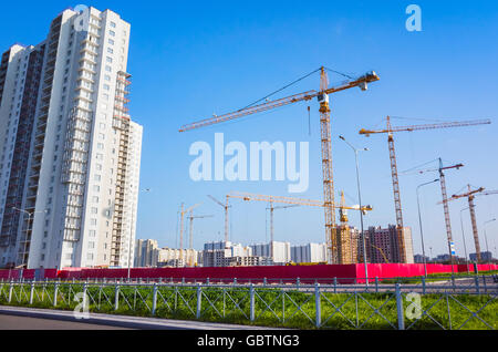 Bloc d'appartements en construction, des grues de travail sont sous ciel bleu Banque D'Images