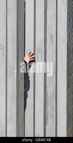 Un visiteur touche un pilier au mémorial des victimes des attentats terroristes du 7 juillet 2005 à Londres, à Hyde Park, Londres. Banque D'Images