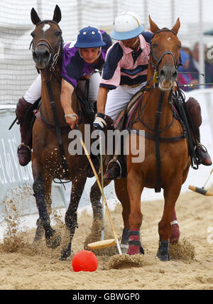 Les équipes se disputent pendant les championnats de polo de plage britannique sous des manteaux de pluie et des parasols dans la zone exclusive Sandbanks de Poole, Dorset. Banque D'Images