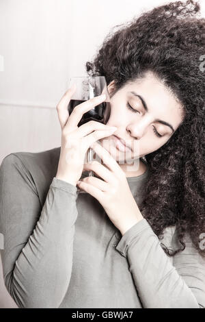 Une jeune femme brésilienne avec un verre de vin rouge. Banque D'Images