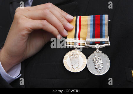 Un officier de marine ajuste ses médailles de campagne en Irak et en Afghanistan après que la duchesse de Cornwall, dans son rôle de Commodore en chef, Royal Naval Medical Services, a remis des médailles de campagne pour des services en Afghanistan au personnel médical du HMS excellent, à Whale Island, Portsmouth. Banque D'Images