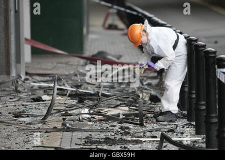 Un officier de police inspecte les débris sur les lieux d'un incendie à Lakanal House à Camberwell, dans le sud de Londres, qui a coûté la vie à six personnes vendredi soir. Banque D'Images