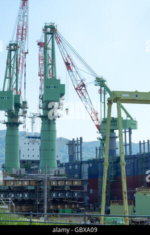 Grues et d'un navire en construction dans un chantier naval au Japon. Banque D'Images