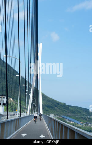 Deux cyclistes traversant le pont de Tatara reliant les îles d'Omishima et Ikuchi dans la mer intérieure de Seto. Banque D'Images