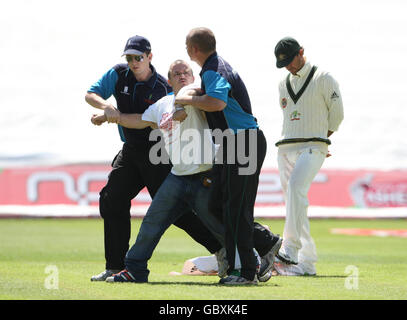 Un manifestant est sorti du champ de jeu par les responsables de la sécurité alors que le capitaine d'Australie Ricky Ponting (à droite) lance une bannière laissée derrière lui au cours du cinquième jour du premier match du npower Test à Sophia Gardens, à Cardiff. Banque D'Images