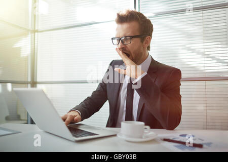 Le bâillement ennuyé businessman working with laptop in office Banque D'Images