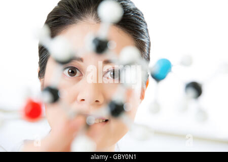 Asian female scientist Examining les éléments constitutifs de la vie à la recherche en laboratoire à travers le modèle moléculaire Banque D'Images