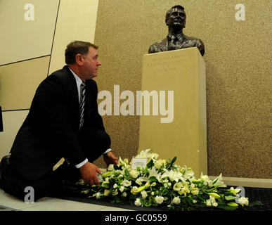 Un membre du personnel de Newcastle Utd dépose des fleurs à la statue de Sir Bobby Robson, à l'entrée des joueurs du parc St James' Park, à Newcastle. Banque D'Images