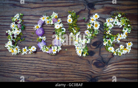 Inscription L'amour fait de fleurs et de feuilles sur fond de table en bois vintage. Mot amour en fleurs.vue d'en haut. Banque D'Images