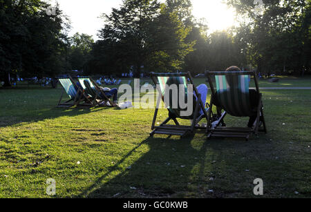 Les gens s'imprégnent des derniers moments du soleil du soir sur les transats du parc St James's de Londres. Banque D'Images