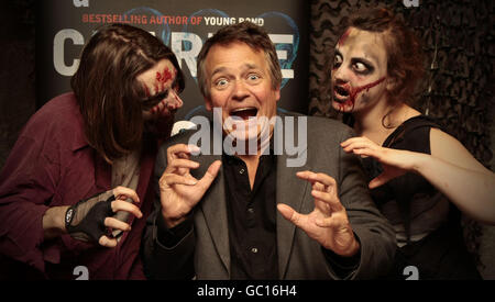 Photo autonome. Le comédien et auteur Charlie Higson est entouré de « zombies » alors qu'il signe des copies de son nouveau livre pour enfants « The Enemy » au London Bridge Experience. Banque D'Images