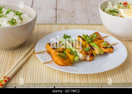 Filet de tilapia asiatique sur une brochette, servi avec riz, salade et citron Banque D'Images