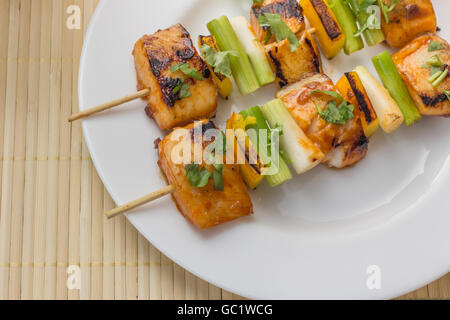 Filet de tilapia asiatique sur une brochette, servi sur une plaque blanche Banque D'Images