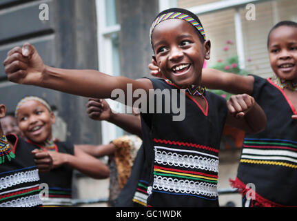 Les enfants du chœur africain des enfants aident la chanteuse Annie Lennox à dévoiler un mémorial à Nelson Mandela, où la pierre porte l'inscription de la Fondation 46664 de l'association caritative Nelson Mandela sur le SIDA, à l'extérieur des chambres de ville d'Édimbourg. Banque D'Images