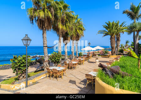 Palmiers et de tables de restaurant sur la promenade côtière à Puerto de la Cruz, Tenerife, Canaries, Espagne Banque D'Images