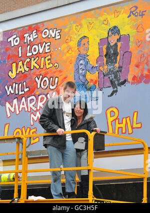 Phil Lee, de Suffolk, propose à la petite amie Jackie Howarth un panneau d'affichage peint par Rolf Harris dans le cadre d'une campagne de Cadbury's pour promouvoir le chocolat Wispa Gold. Banque D'Images