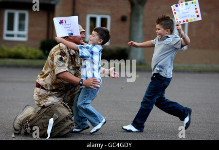 Le sergent d'état-major Kevin Vaughan est accueilli par ses fils Owen, cinq ans, à gauche, et Bradley, 6 ans, En 75, l'ingénieur royal et les spécialistes de la recherche et de l'élimination des bombes du corps logistique royal retournent à Carver Barracks, Wimbish, Essex, après six mois en Afghanistan. Banque D'Images