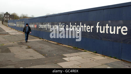 Un homme passe devant un panneau de développement tandis que d'anciens bâtiments sont démolis ou démolis au fur et à mesure que le nouveau développement progresse à l'usine MG Rover cars de Longbridge, Birmingham Banque D'Images