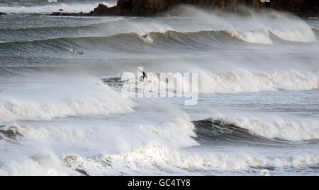 Un surfeur aime le surf à Tynemouth, North Tyneside, Tyne et de l'usure, comme les averses lourdes et les vents forts qui ont frappé une grande partie du Royaume-Uni. Banque D'Images