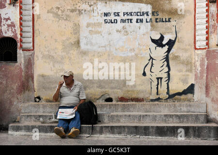 Man reading newspaper sur les mesures de Teatro Cespedes, Regla, Cuba Banque D'Images