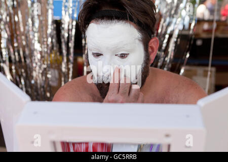 L'application de la base de l'homme blanc le maquillage sur le visage - USA Banque D'Images