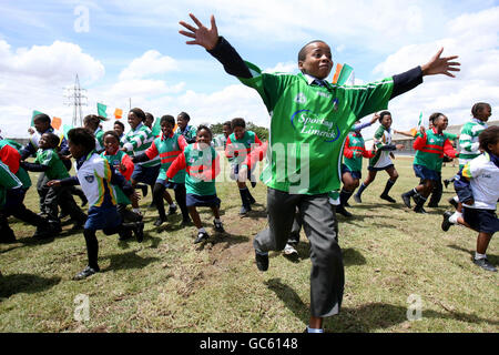 Les enfants portant des maillots irlandais de football gaélique célèbrent la pose de leur nouveau terrain de football et de leur nouveau terrain de jeu d'aventure à l'école primaire d'Enkululekweni, dans le canton de Wallacadene, au Cap, en Afrique du Sud.Le terrain de jeu et le terrain de jeu ont été construits par des volontaires irlandais avec la fiducie du canton de Niall Mellon. Banque D'Images