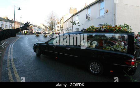 Le corbillard portant le cercueil de PC Bill Barker passe par les rues d'Egremont pour son service funéraire à l'église de St Mary et St Michael dans sa ville natale d'Egremont, Cumbria. Banque D'Images