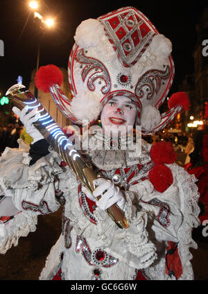 Un participant tient le Queen's Baton pendant la parade des lumières de la fête du Homecoming, une procession éclairée par une torche dans le centre-ville de Glasgow, en commençant à George Square et culminant en concert à St Andrews in the Square. Banque D'Images