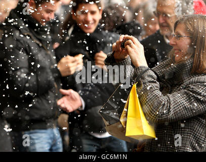 Un acheteur de Noël prend des photos dans une douche de neige artificielle sur Oxford Street, dans le centre de Londres, lors de la 5ème édition annuelle très importante de l'événement piétons. Banque D'Images