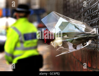 Un policier se tient près des fleurs laissées sur le chemin Yoakley, à Stoke Newington, dans le nord de Londres, après qu'un homme de 19 ans ait été trouvé poignardé à mort dans la route. Banque D'Images