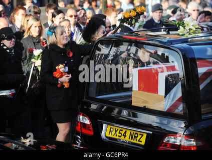 Nicola, l'épouse du caporal Loren Marlton-Thomas, se met en avant pour placer des fleurs sur un corbillard, car elle porte le cercueil de son mari à travers la ville de Wootton Bassett dans le Wiltshire, après son rapatriement à RAF Lyneham, dans le Wiltshire. Banque D'Images