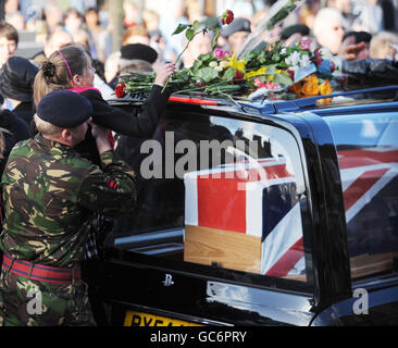 Un enfant est levé pour placer une rose sur un corbillard alors que les cercueils du Caporal Loren Christopher Marlton-Thomas, 28 ans, du 33 Engineer Regiment et du Rifleman Andrew Ian Fetiman, 23 ans, du 7e Bataillon, les Rifles passent par la ville de Wootton Bassett dans le Wiltshire après leur rapatriement à la RAF Lyneham, Wiltshire. Banque D'Images