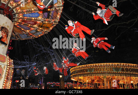Les personnes vêtues de Santa apprécient les manèges du champ de foire de Leicester Square à Londres tout en prenant part à Santacon. Banque D'Images