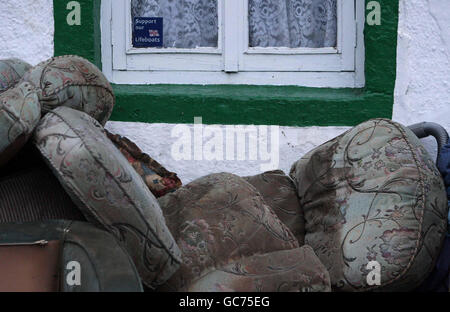 Des débris se trouvent à l'extérieur d'une maison à côté du Cocker, dans le centre-ville de Cockermouth, à la suite des récentes inondations. Banque D'Images