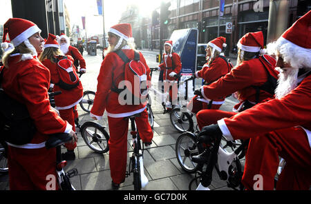 Des gens vêtus de Santa sur Gocycles à l'extérieur de la gare de Waterloo à Londres pour promouvoir la fibre de carbone, électrique, vélo pliant. Banque D'Images