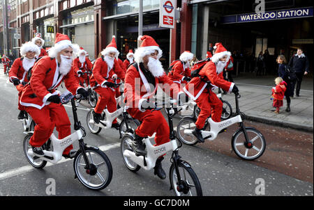 Des gens vêtus de Santa sur Gocycles à l'extérieur de la gare de Waterloo à Londres pour promouvoir la fibre de carbone, électrique, vélo pliant. Banque D'Images