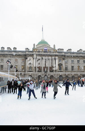 Les patineurs apprécient le temps d'hiver à la patinoire Somerset House tandis que la neige tombe au-dessus de Londres. Banque D'Images