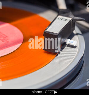 Bras de platine sur l'orange vinyl record close up Banque D'Images
