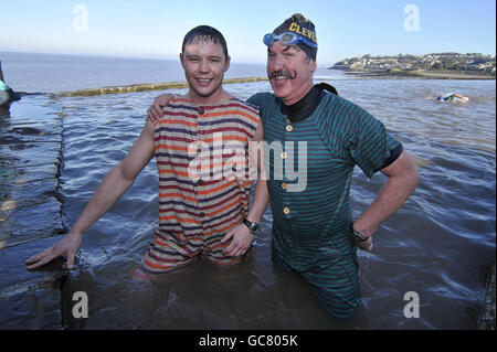 Justin Blackmore, 26 ans, (à gauche) et Andy Smith, 35 ans, tous deux de Clevedon, se joignent à d'autres nageurs en costumes de bain de style victorien lors de la baignade annuelle du jour du nouvel an dans la marina de Clevedon, où la température est juste au-dessus du point de congélation. Banque D'Images