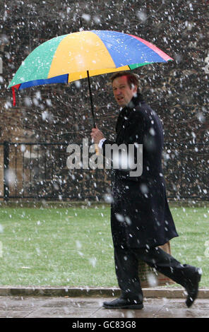 Un homme se couche sous un parapluie alors que la neige tombe à Westminster, dans le centre de Londres. Banque D'Images