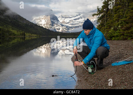 Un camping-utilise un filtre pour recueillir de l'eau potable de Cortés Lac au parc national des Glaciers dans la région de West Glacier dans le Montana. Banque D'Images