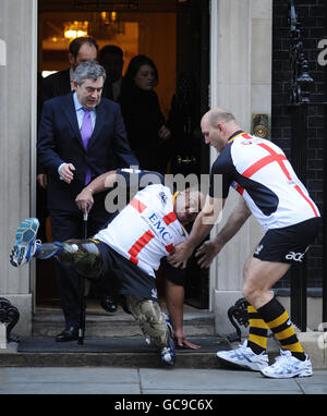 Le premier ministre Gordon Brown et le joueur de rugby Lawrence Dallaglio (à droite) aident Derek Derenalagi (au centre) à se trouver à la porte du 10 Downing Street, Londres. L'ancien soldat qui a perdu les deux jambes en Afghanistan en 2007 était là pour promouvoir un match de rugby du Saint-Georges Day afin de recueillir de l'argent pour aider les héros. Banque D'Images