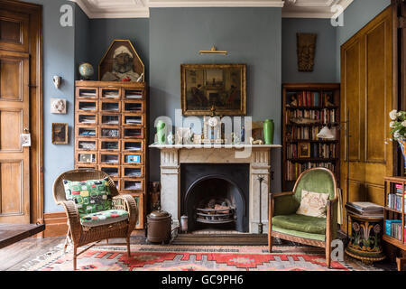 1930 L'unité d'entreposage des tabliers avec horloge colonial et une chaise et fauteuil capitonné velours ouvrir dans Nottinghill home, Londres, Royaume-Uni Banque D'Images