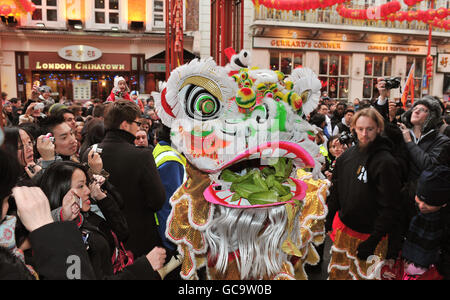 Les gens célèbrent le début des célébrations du nouvel an chinois tandis qu'un lion chinois traditionnel traverse les rues bondées de Chinatown, Londres. Banque D'Images