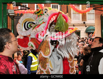 Les gens célèbrent le début des célébrations du nouvel an chinois tandis qu'un lion chinois traditionnel traverse les rues bondées de Chinatown, Londres. Banque D'Images