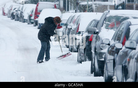 Un homme élimine la neige autour de sa voiture dans Great Chart près d'Ashford, dans le Kent, après une nuit de fortes chutes de neige. Banque D'Images