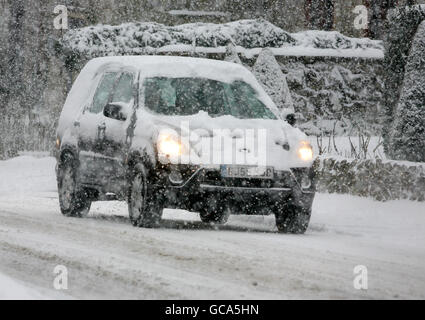 Un chauffeur traverse Great Chart près d'Ashford, dans le Kent, après une nuit de neige abondante. Banque D'Images