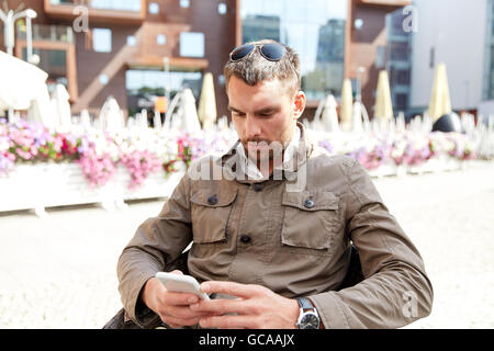 Young man texting on smartphone à ville terrace Banque D'Images