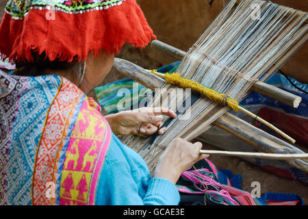 Femme péruvienne en costume traditionnel tissu tissage sur un métier à tisser à la main dans les montagnes des Andes, Pérou Banque D'Images