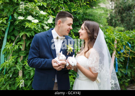 Wedding couple holding sont deux petits lapins, l'heure d'été Banque D'Images